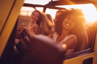 Two ladies driving a roofless geep in the sunset