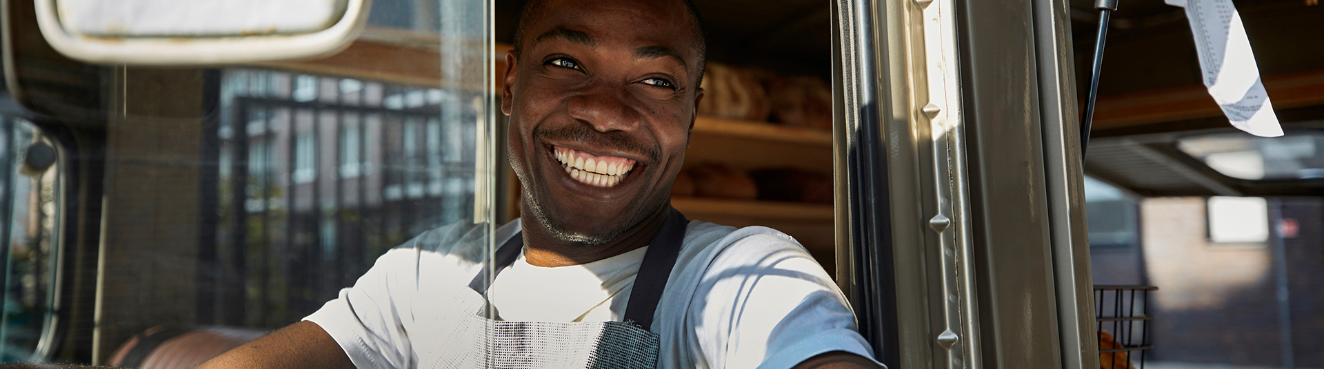 A man driving a truck smiling through the window